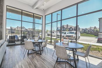 a dining area with tables and chairs and large windows